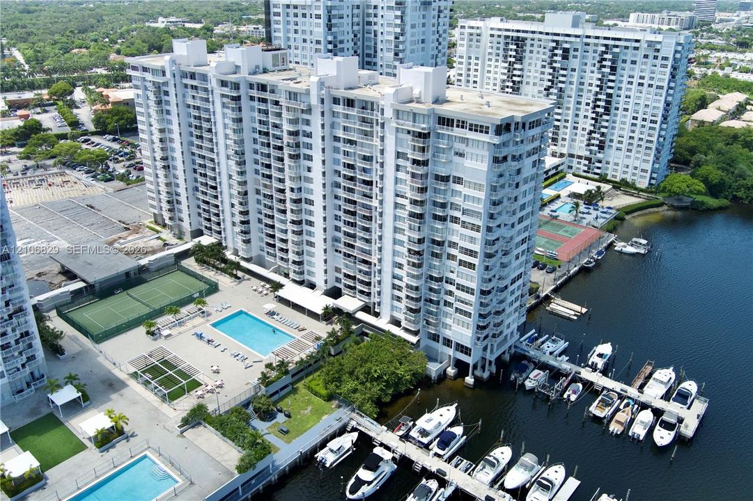 High-rise building featuring a private marina with deep-water boat slips, outdoor swimming pools, tennis courts, and landscaped grounds
