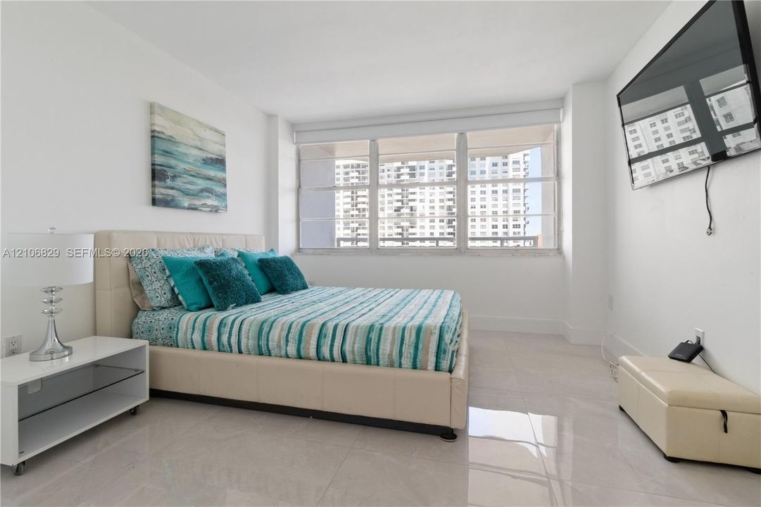 Neutral-toned oversized tile flooring, expansive window wall, and smooth white wall finishes