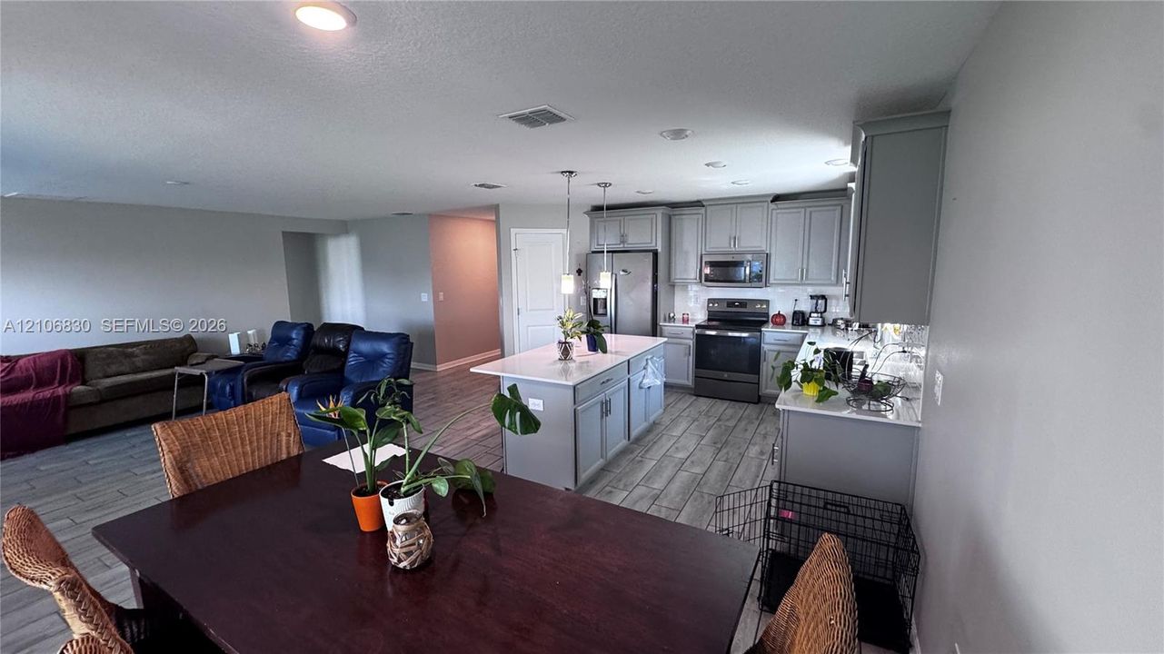 Kitchen featuring a central island with a stone-finish countertop, grey cabinetry, stainless steel appliances, recessed lighting, and wood-finish tile flooring