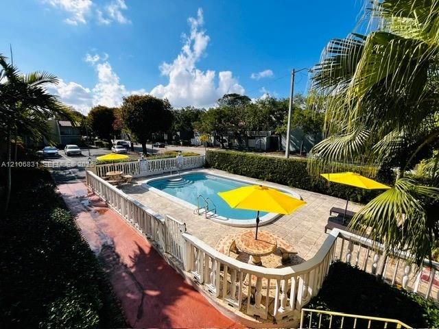 In-ground pool with integrated steps, surrounded by stone-finish decking and a balustrade perimeter fence, featuring mature landscaping