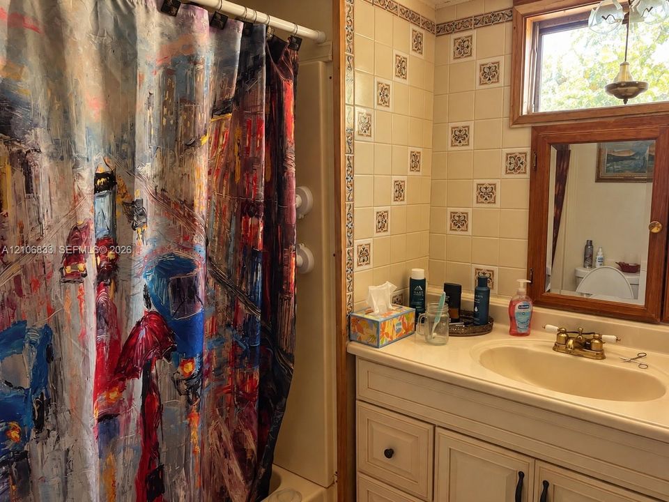 Bathroom featuring a white vanity cabinet with an integrated sink, a wood-framed medicine cabinet, and tiled wall accents