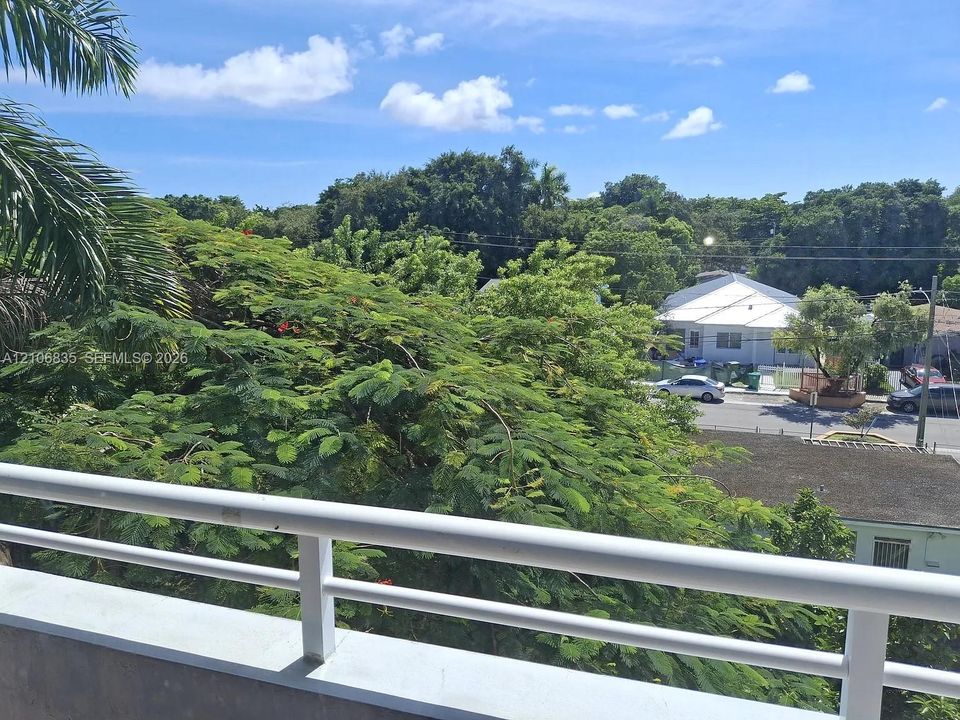 Elevated balcony featuring a white metal railing and greenery-rich surroundings