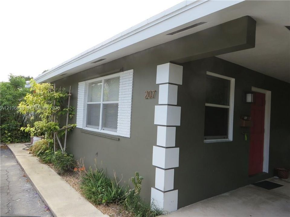 Exterior facade featuring painted stucco, decorative white brick shutters, a covered entry, and a structural column with raised block detailing