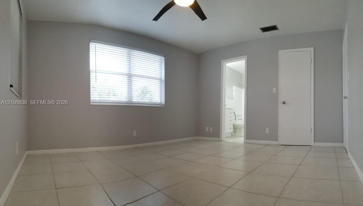 Interior space featuring large-format ceramic tile flooring, neutral wall paint, a ceiling-mounted light fixture, and horizontal window blinds