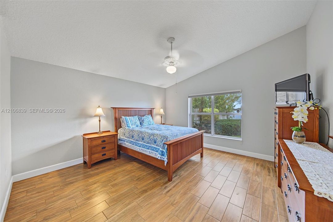 Vaulted ceilings, wood-finish tile flooring, and a central ceiling fan