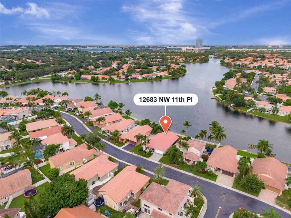 Waterfront residence featuring tile roofing, paved driveway, and mature palm trees situated on a canal