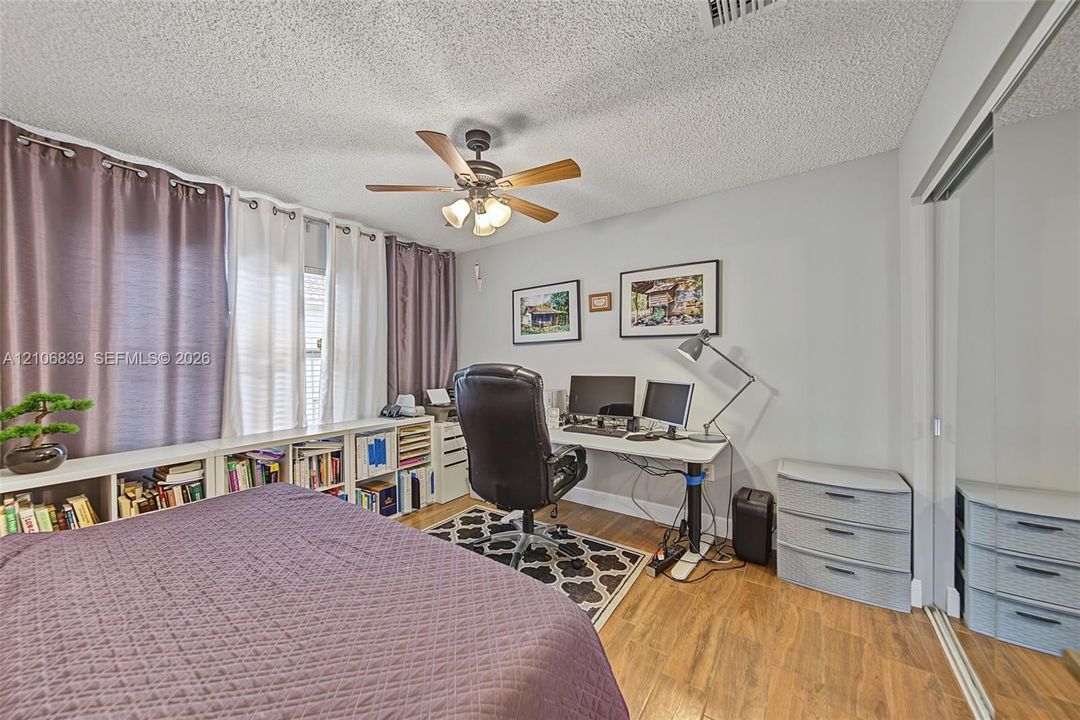 Wood-finish flooring, ceiling fan with integrated lighting, and mirrored sliding closet doors