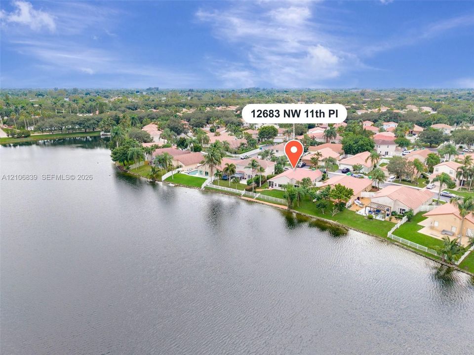 Waterfront property featuring a tile-roofed residence, exterior green space, and perimeter fencing