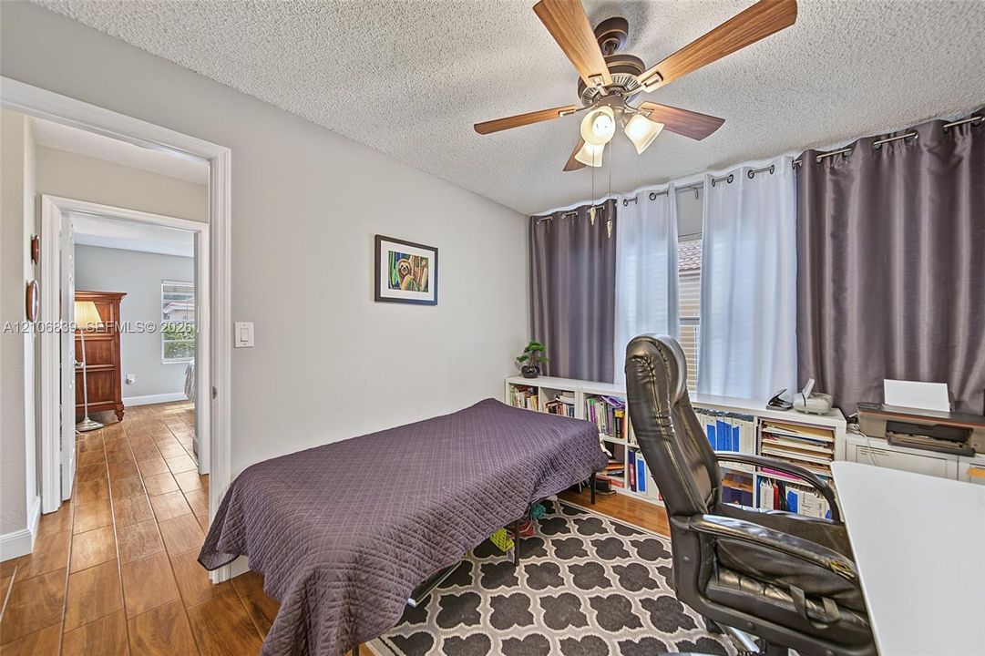 Room featuring wood-finish tile flooring, built-in shelving, and a ceiling fan with integrated lighting