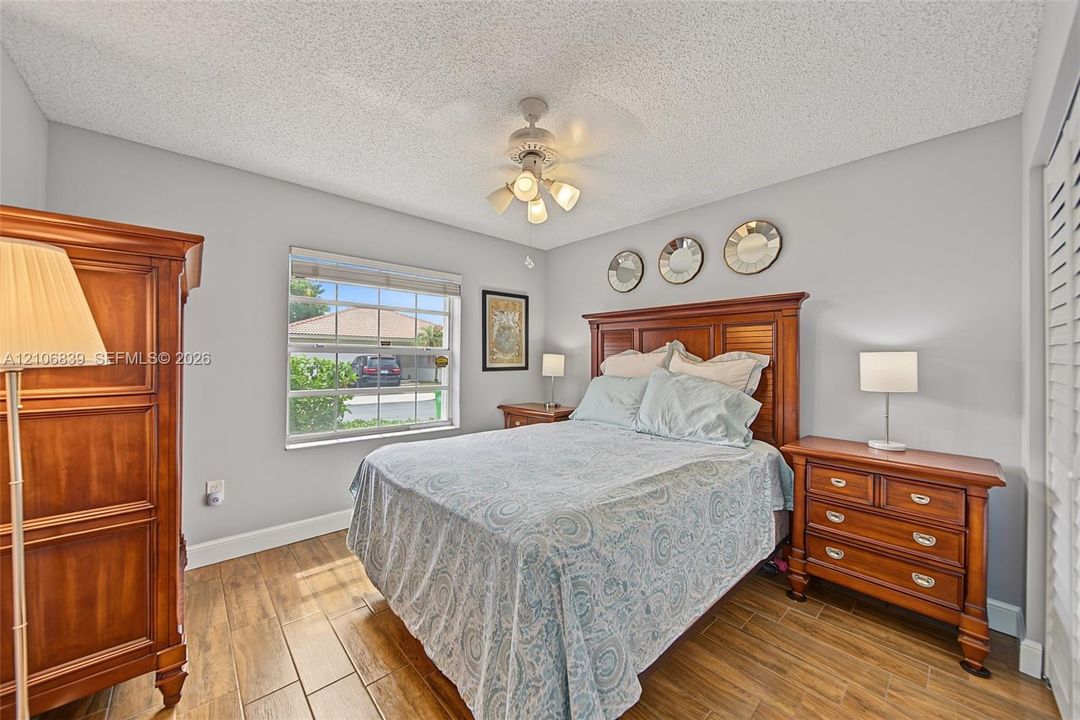 Wood-finish flooring, multi-light ceiling fan, and window with muntin detailing