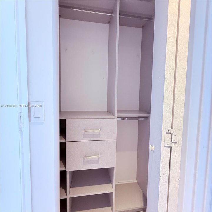 Custom storage system featuring two stacked drawers, open shelving, and integrated hanging rods with metal hardware