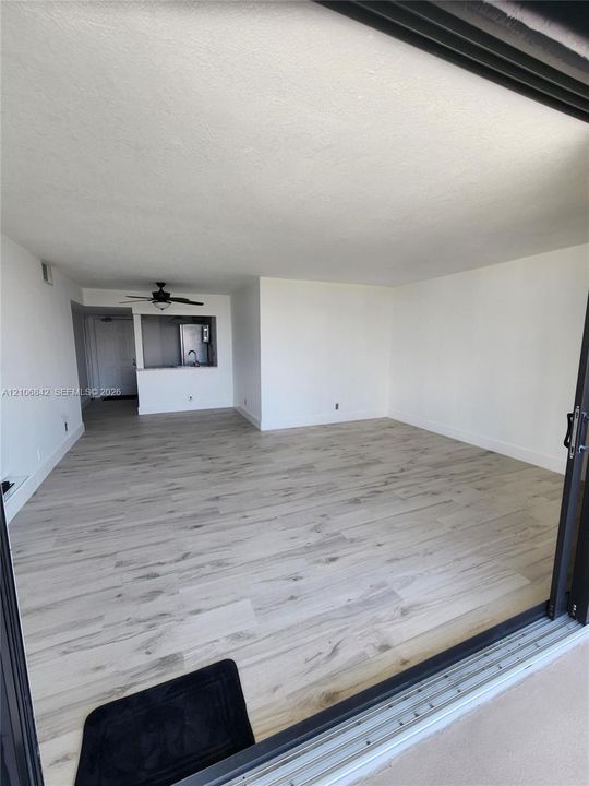 Open interior featuring wood-finish flooring, recessed ceiling lighting, and a pass-through opening to the kitchen