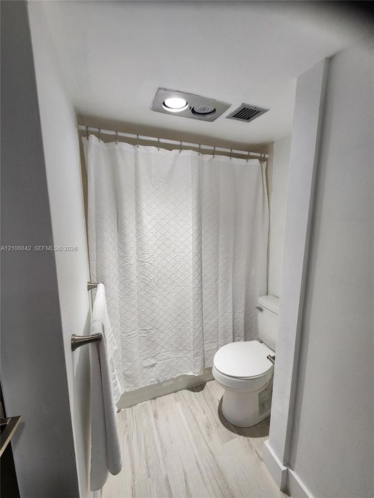 Bathroom featuring wood-finish flooring, a wall-mounted brushed nickel towel bar, and a recessed ceiling light fixture