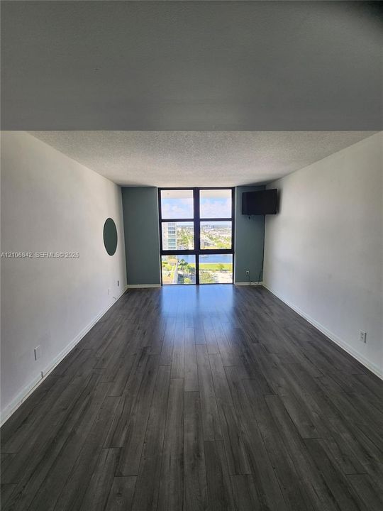 Living area featuring wood-finish flooring, floor-to-ceiling windows, and painted accent walls
