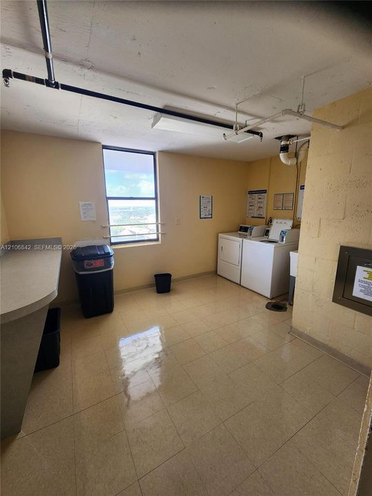 Laundry room featuring tile flooring, a dedicated workstation with a solid-surface countertop, and a window with exterior exposure