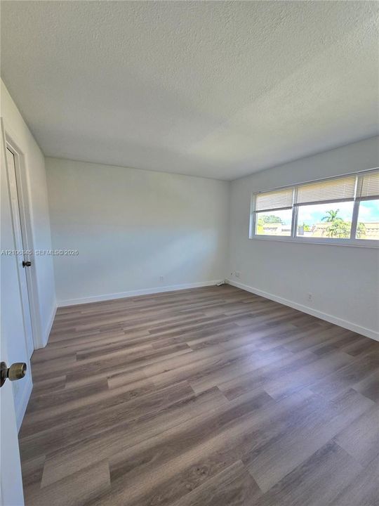 Neutral-toned interior space featuring wood-finish flooring and a wide, multi-pane window