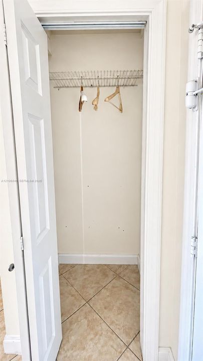 Reach-in closet featuring a hinged panel door, integrated wire shelving, and neutral tile flooring