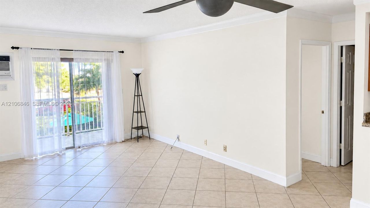Interior space featuring large-format diagonal tile flooring, crown molding, a multi-blade ceiling fan, and sliding glass doors with direct access to a balcony