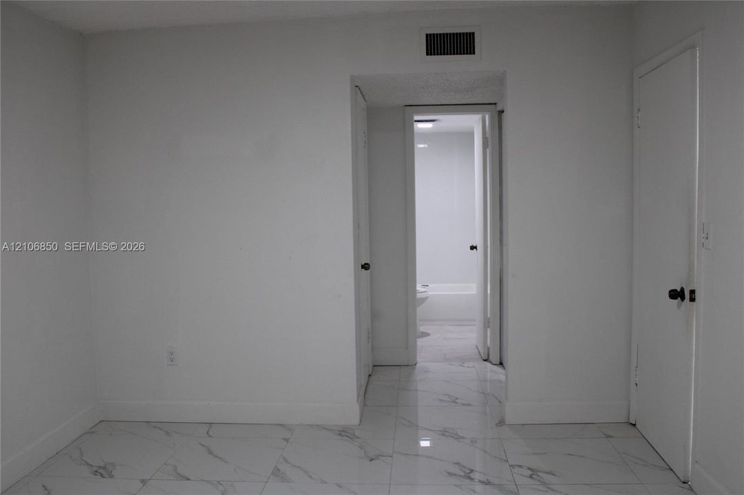 Polished large-format tile flooring with marble-finish detailing, solid-core interior doors, and neutral wall finishes