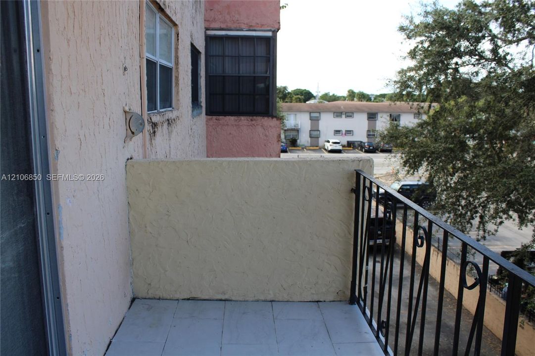 Balcony featuring a tile floor, textured exterior wall, and metal railing
