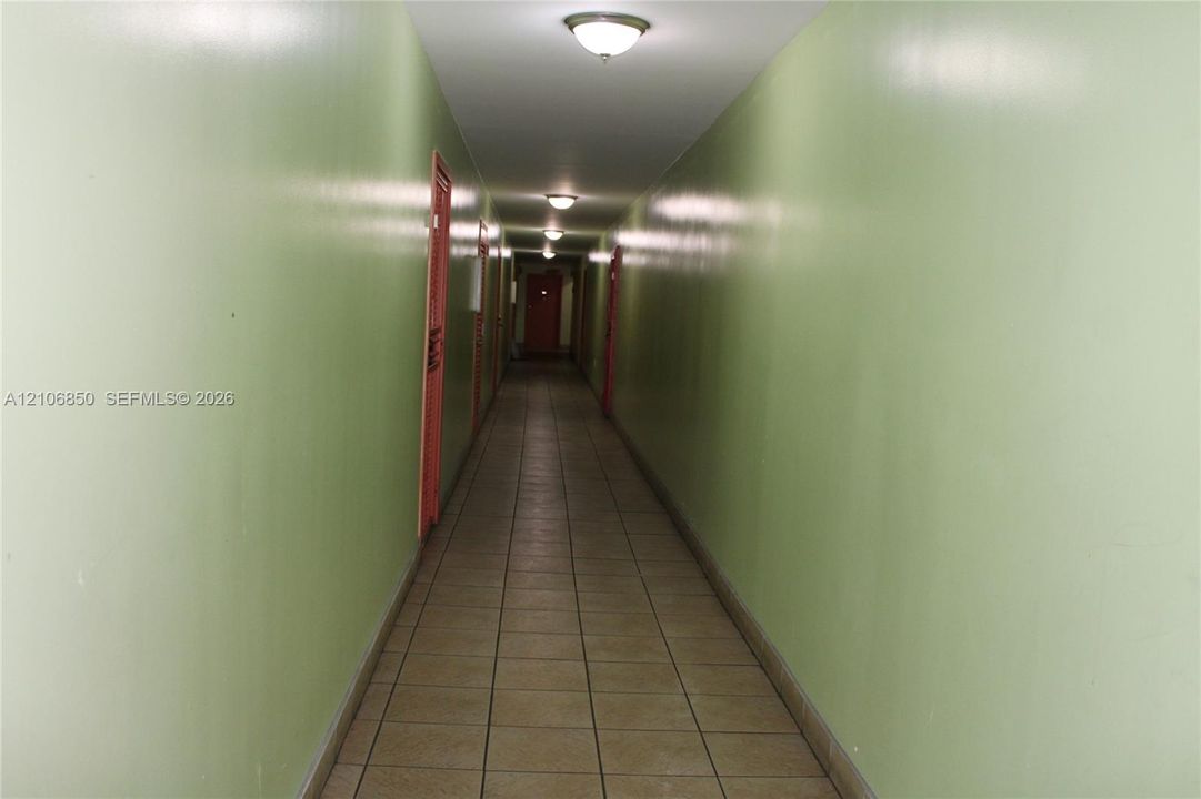 Hallway featuring ceramic tile flooring, flush-mount ceiling lighting, and solid-core doors