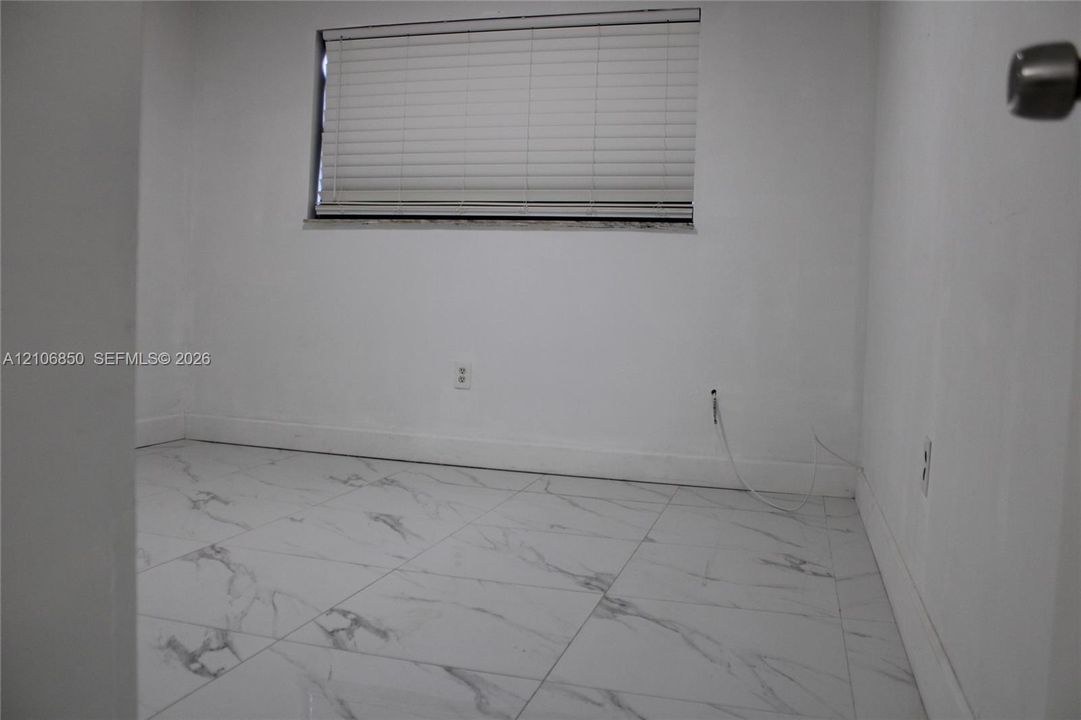 Interior space featuring white stone-finish tile flooring and an integrated horizontal window blind