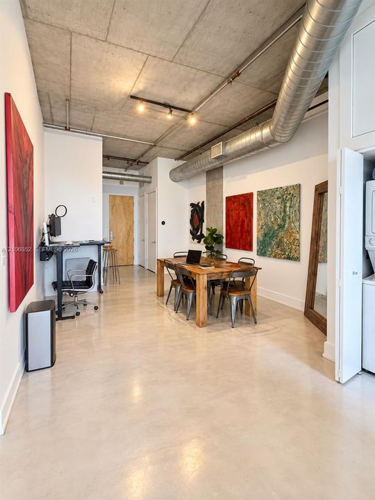 Industrial-style interior featuring exposed concrete ceilings, polished concrete flooring, exposed ductwork, track lighting, and a bi-fold door closet