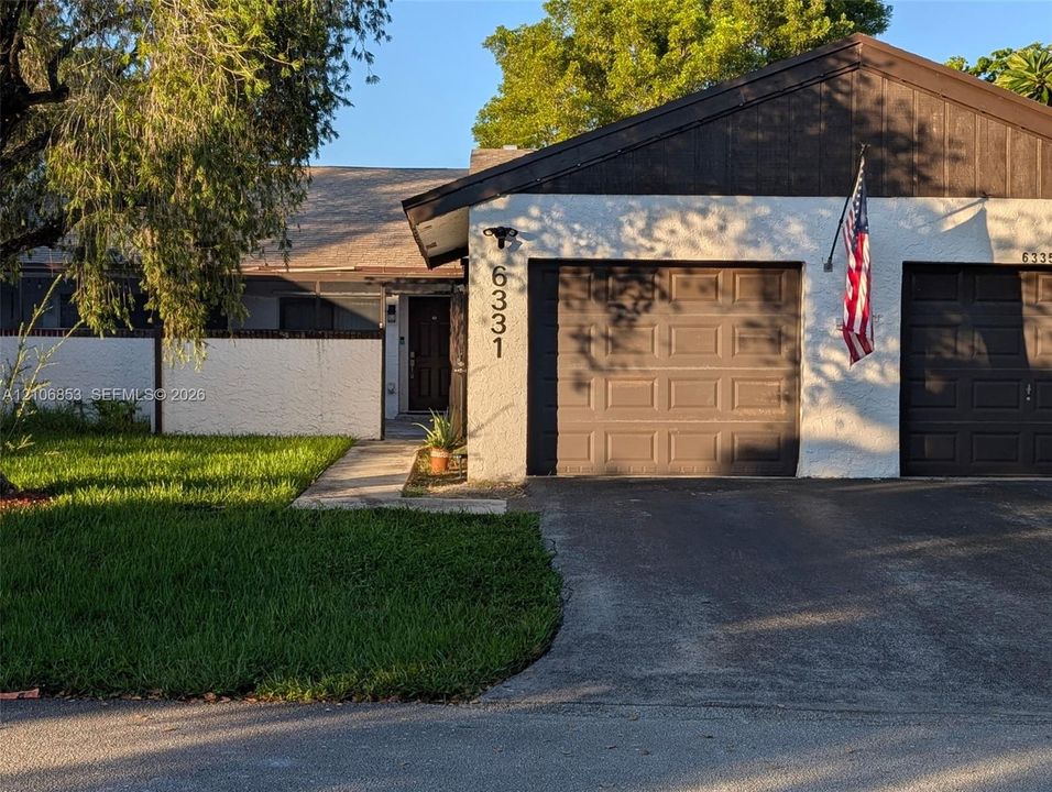 Stucco exterior residence featuring a dual-bay garage, asphalt driveway, and concrete walkway