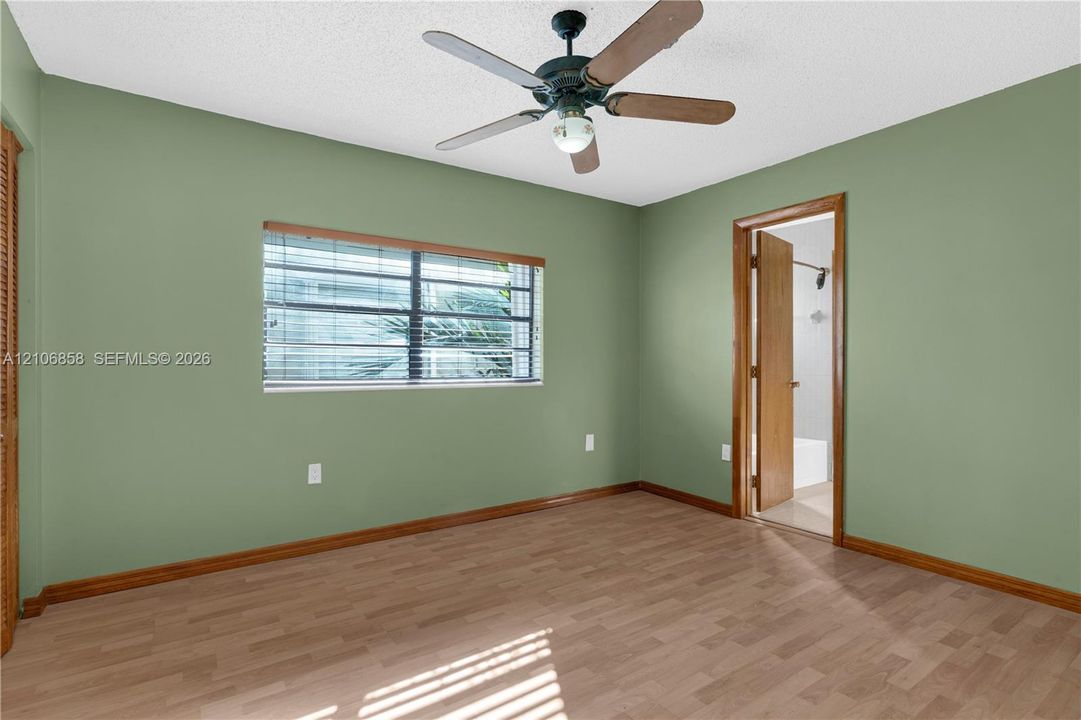 Interior space featuring wood-finish flooring, a multi-blade ceiling fan, and window with integrated blinds