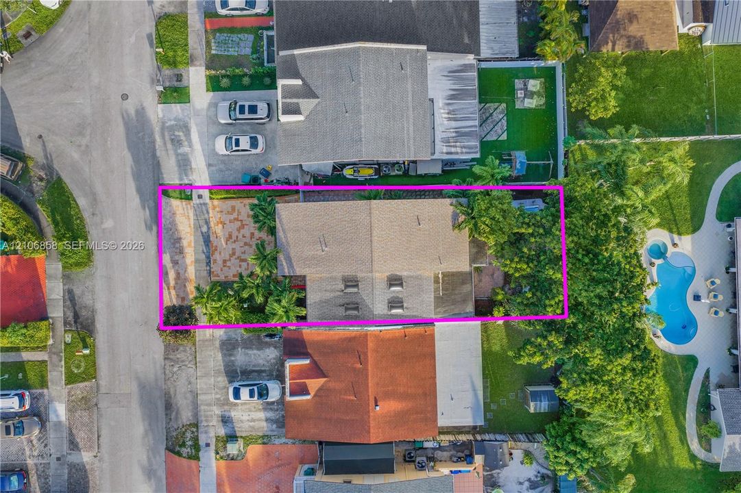 Aerial perspective showcasing a parcel featuring a paved front courtyard, gable roofline, and mature landscaping