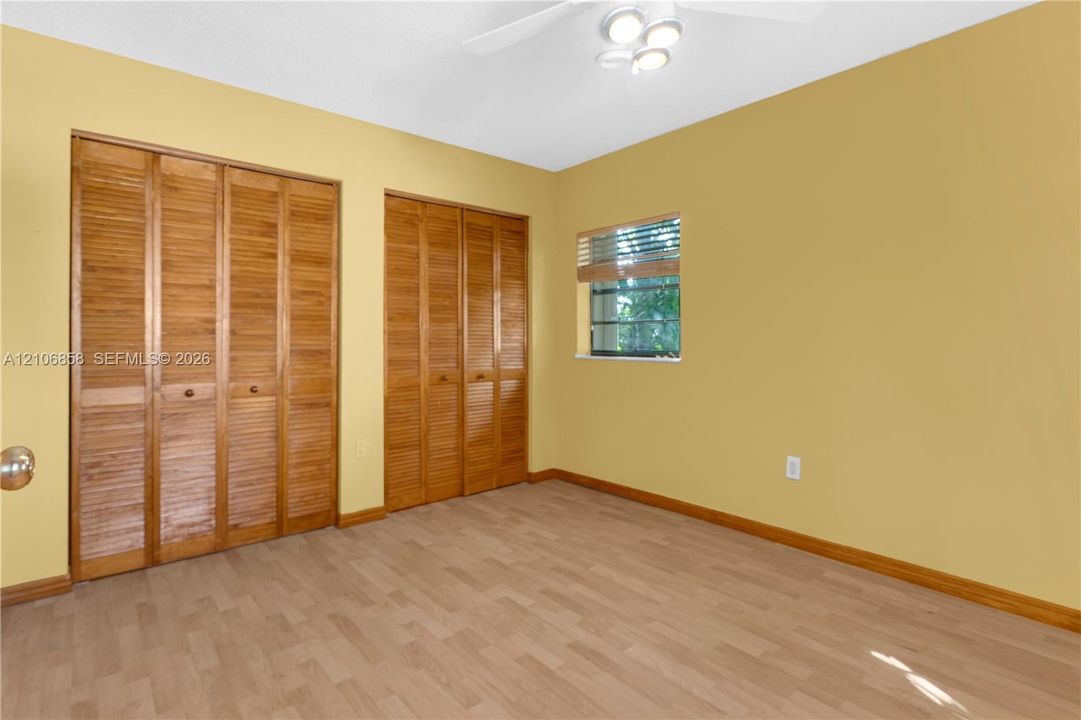 Wood-finish flooring, two sets of bifold wooden closet doors, and a ceiling-mounted light fixture