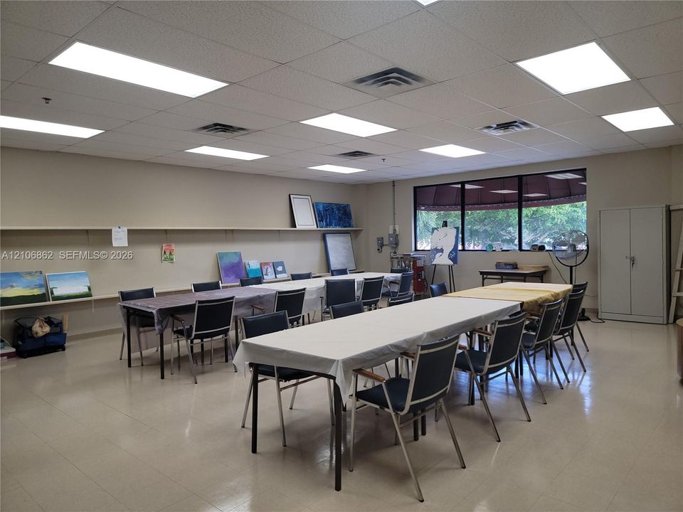 Expansive room featuring a drop ceiling with recessed rectangular lighting, tile flooring, large multi-pane windows, and extensive wall-mounted shelving