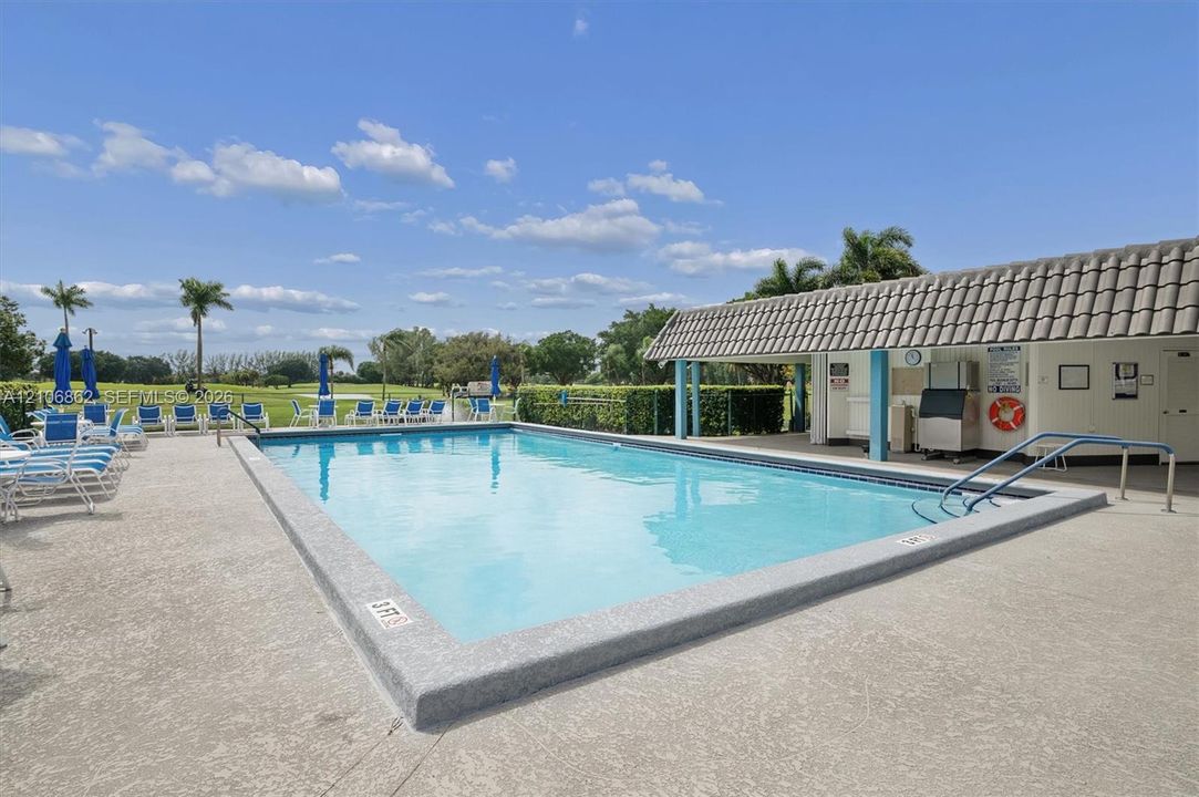 Swimming pool with concrete decking, metal safety rails, and covered poolside structure featuring a tile roof