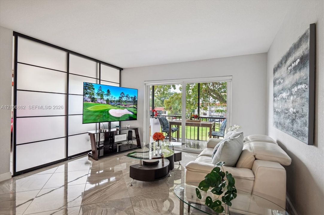 Large-format tile flooring, sliding glass balcony doors, and a black-framed frosted glass partition wall