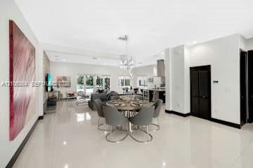 Open-concept interior featuring large-format tile flooring, a stone-accent wall, recessed lighting, and a crystal chandelier
