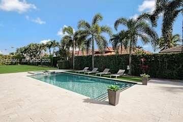 Outdoor living area featuring a covered pergola, concrete paver patio with grass joints, rectangular swimming pool, and privacy hedges