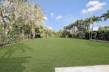 Single-story exterior featuring a concrete driveway, two-car garage, manicured lawn, and mature palm trees