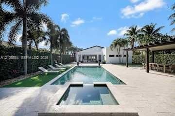 Expansive rear grounds featuring a manicured lawn, established perimeter hedges, and mature palm trees