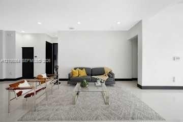 Open-concept living space featuring high ceilings with recessed lighting, crisp white wall finishes, polished hard-surface flooring, and high-contrast dark door frames