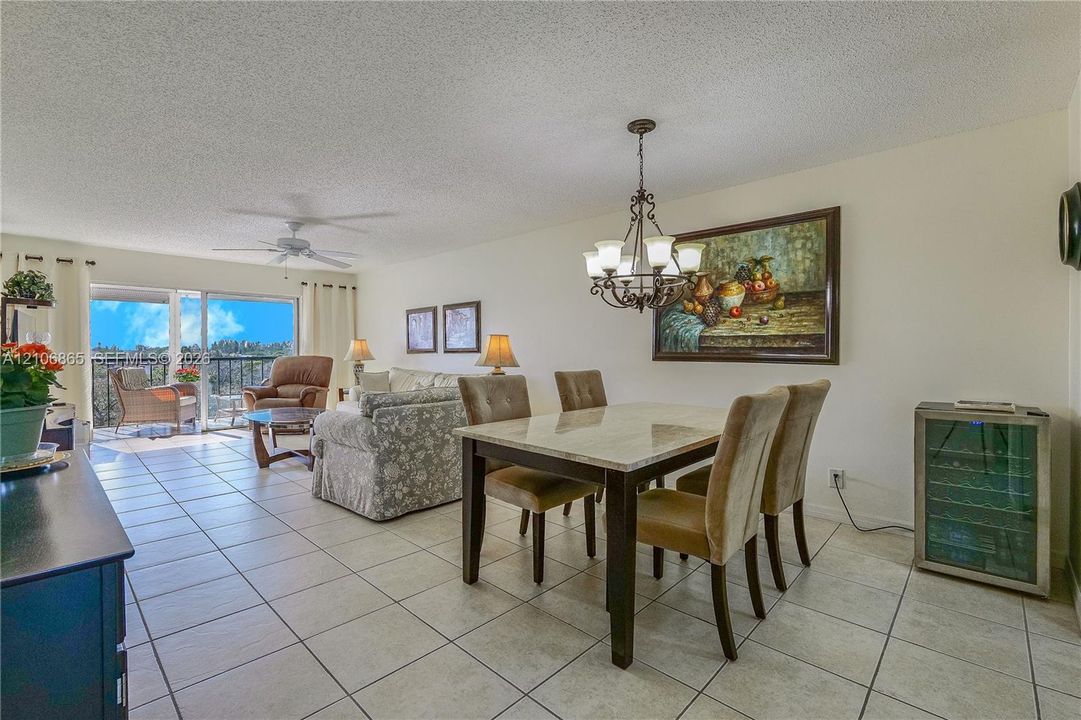 Open-concept floor plan featuring tile flooring, a multi-arm metal chandelier, recessed lighting, and a built-in glass-door beverage refrigerator