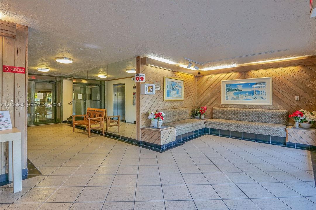 Lobby featuring diagonal wood paneling, tiled flooring, built-in seating, recessed lighting, and a metal elevator entrance