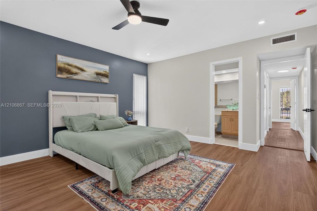 Room featuring wood-finish flooring, a dark accent wall, and a contemporary ceiling fan with integrated lighting
