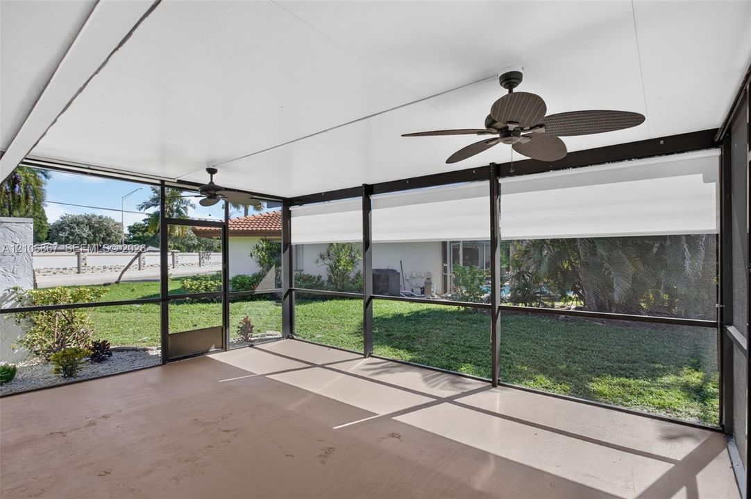 Screened-in patio featuring a concrete floor, two ceiling fans, retractable privacy shades, and an aluminum frame enclosure
