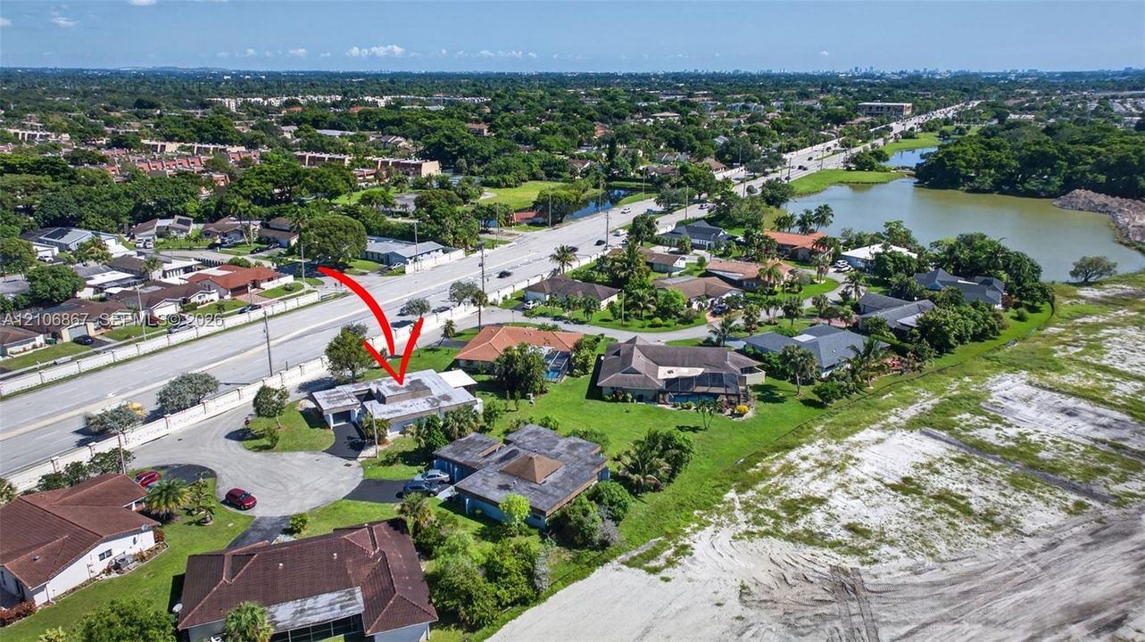 Aerial perspective of property featuring an asphalt driveway, concrete roof tiles, and manicured landscaping
