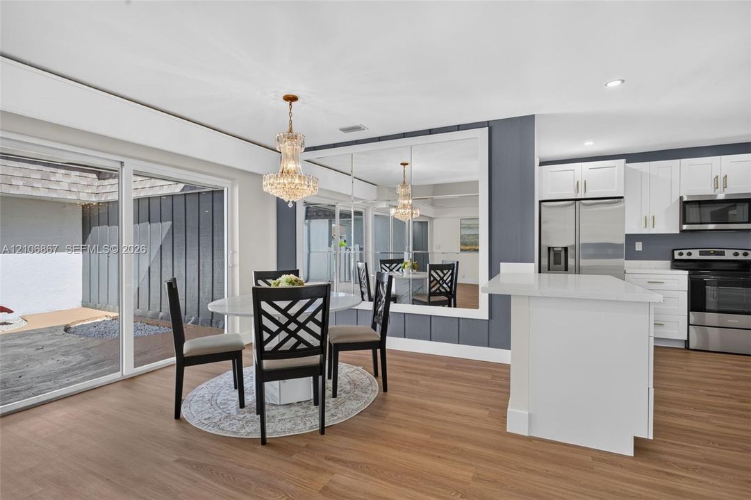 Dining area featuring wood-finish flooring, a crystal chandelier, a large wall mirror with trim, and a glass sliding door