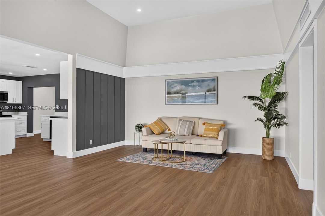 Vaulted ceilings featuring recessed lighting, wood-finish flooring, and a vertical paneled accent wall