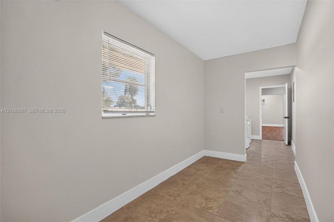 Neutral-toned interior room featuring tile flooring, smooth walls, and a window with horizontal blinds