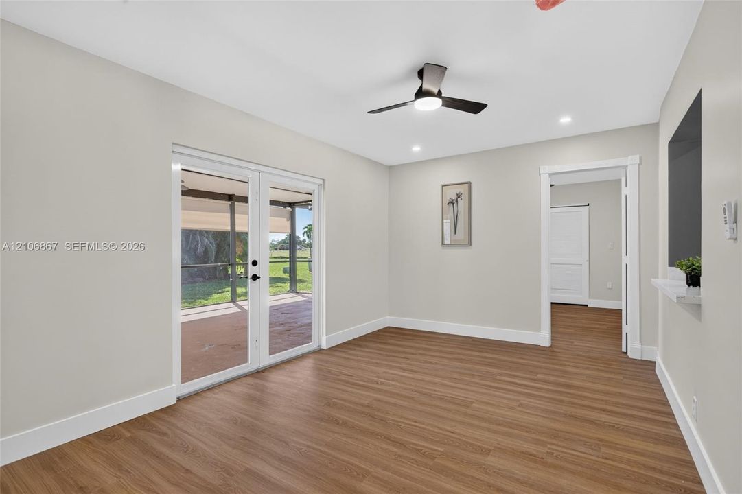 Interior space featuring wood-finish flooring, recessed lighting, a modern ceiling fan, and double glass doors opening to a screened-in lanai