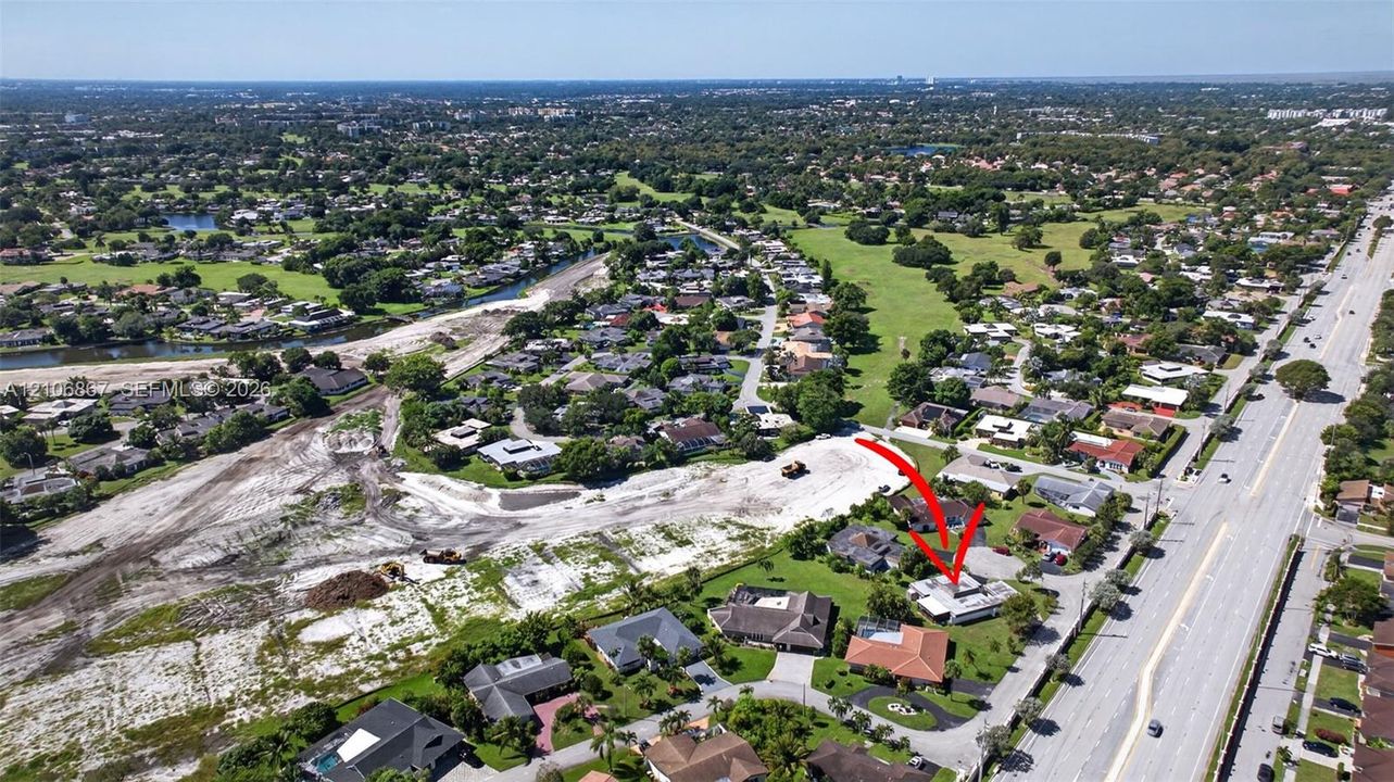 Aerial perspective featuring a single-family residence with a tile roof and a private swimming pool, situated on a corner lot
