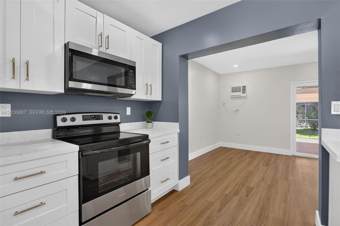 Kitchen featuring white cabinetry, solid-surface countertops, stainless steel appliance suite, and wood-finish flooring
